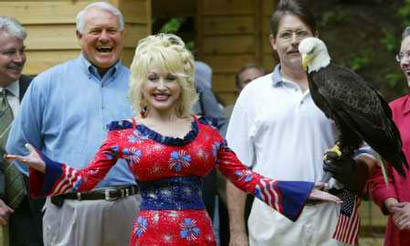 Entertainer Dolly Parton jokes alongside Challenger, a 15-year-old American Bald Eagle at the National Zoo in Washington, July 2, 2003. Parton, a contributor to the preservation of the once-endangered symbol of Amercian freedom, was present to launch the zoo's pre-July 4 Independence Day Bald Eagle Refuge Exhibit to celebrate the national bird and the 100th anniversary of the founding of the National Wildlife Refuge System. Challenger is cared for by the non-profit American Eagle Foundation, headquarted at Dollywood in Pigeon Forge, TN. Deputy Interior Secretary Steve Griles (left) and American Eagle Foundation President Al Cecere (right). — REUTERS/Jason Reed